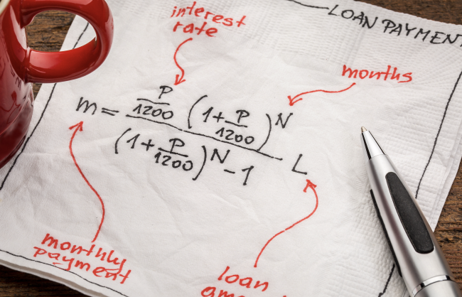 loan payment equation sketched on a white napkin with a cup of coffee